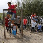 Syrian Kurdish migrant climbs over the fence on the Hungarian-Serbian border near Asotthalom