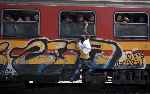 A migrant tries to board a train through the window at Gevgelija train station in Macedonia, close to the border with Greece, August 15, 2015. In the past month, an estimated 30,000 refugees have passed through Macedonia, another step in their uncertain search for a better life in western Europe. REUTERS/Stoyan Nenov
