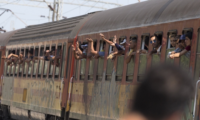 Migrants wave as their train leaves Gevgelija station in Macedonia