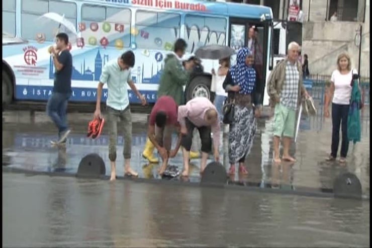 USKUDAR'DA ANIDEN BASTIRAN YAGMUR, YAYA VE TASIT TRAFIGINI OLUMSUZ ETKILEDI. TASITLAR YOLDA ILERLEMEKTE ZORLUK CEKERKEN, VATANDASLAR AYAKKABILARINI CIKARTARAK YOLU ASTI. (FOTO: UGUR AYAZSIN/ISTANBUL, DHA)