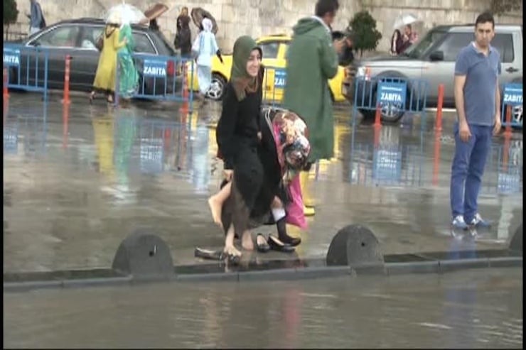 USKUDAR'DA ANIDEN BASTIRAN YAGMUR, YAYA VE TASIT TRAFIGINI OLUMSUZ ETKILEDI. TASITLAR YOLDA ILERLEMEKTE ZORLUK CEKERKEN, VATANDASLAR AYAKKABILARINI CIKARTARAK YOLU ASTI. (FOTO: UGUR AYAZSIN/ISTANBUL, DHA)
