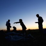 Syrian migrants stand by their sleeping bags on the side of a highway as they rest from their travel towards the Greece border near Edirne