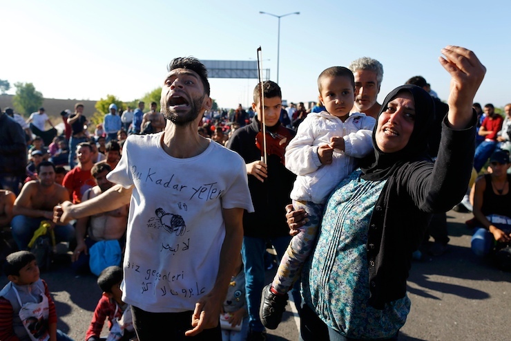 A woman holding a child reacts as Turkish police and gendarmes block migrants on a highway near Edirne, Turkey, September 19, 2015. Hundreds of mainly Syrian migrants remain blocked on western Turkey's border with Greece after camping for several days on the side of the highway. REUTERS/Osman Orsal (TURKEY - Tags: SOCIETY IMMIGRATION POLITICS)