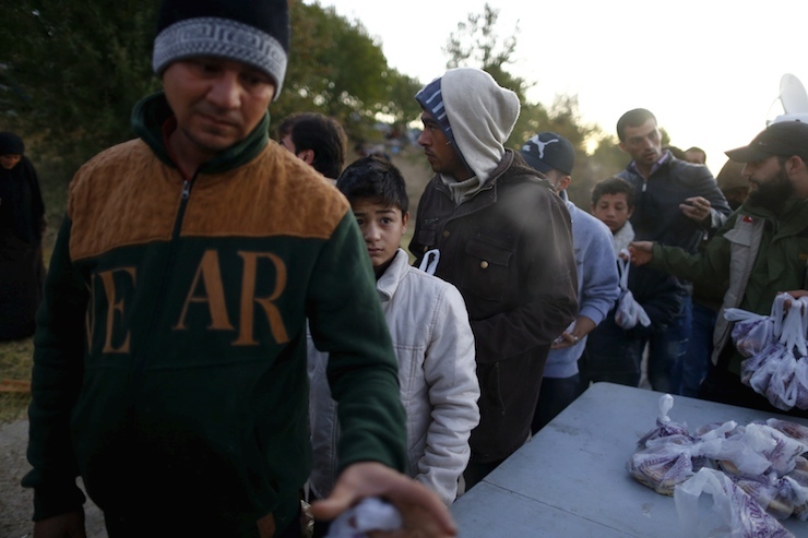 Syrian migrants queue to get food on the side of a highway near Edirne as they rest from their travel towards the Greece border