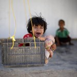 A Syrian refugee child reacts while sitting in a swing in Al Zaatari refugee camp, in the Jordanian city of Mafraq