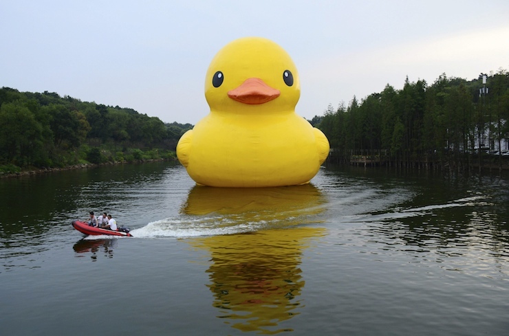 Workers travel on a speed boat past an inflatable Rubber Duck installation by Dutch artist Florentijn Hofman, on a lake at a botanic garden in Changsha, Hunan province, China, September 21, 2015. The 18-metre-high Rubber Duck will be shown to the public in the garden from September 21 to November 22, according to local media. Picture taken September 21, 2015. REUTERS/Stringer TPX IMAGES OF THE DAY CHINA OUT. NO COMMERCIAL OR EDITORIAL SALES IN CHINA