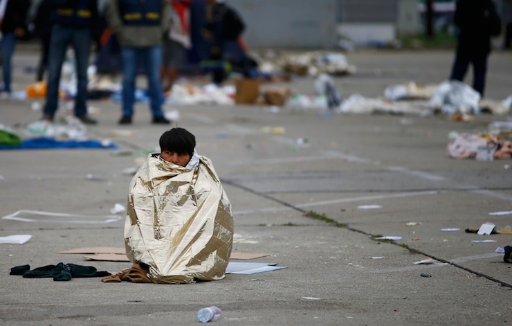 A migrant sits wrapped in an emergency blanket against the cold at the crossing point between Hungary and Austria in Nickelsdorf