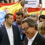 Catalunya's President Artur Mas casts his ballot as people hold Spanish flags and banners behind him at a polling station in Barcelona