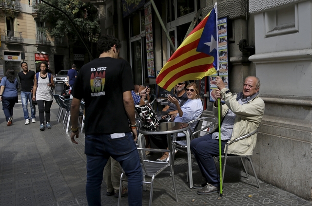 A man holding an "Estelada" flag, a symbol of Catalonian pro-independence, sits in a restaurant in Barcelona