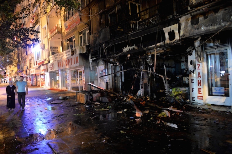 Pedestrians walk past by a damaged shop after it was set on fire by ultra nationalist protesters in Kirsehir,Turkey