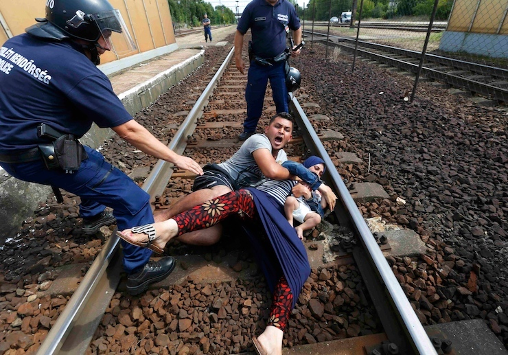 REFILE - PROVIDING ADDITIONAL INFORMATION - Hungarian policemen stand by the family of migrants as they wanted to run away at the railway station in the town of Bicske, Hungary, September 3, 2015. A camp for refugees and asylum seekers is located in Bicske. REUTERS/Laszlo Balogh
