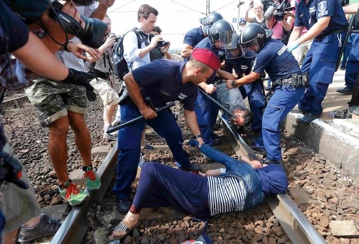 Hungarian policemen detain migrants on the tracks as they wanted to run away at the railway station in the town of Bicske, Hungary, September 3, 2015. A camp for refugees and asylum seekers is located in Bicske. REUTERS/Laszlo Balogh