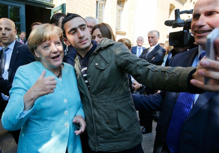 A migrant takes a selfie with German Chancellor Angela Merkel outside a refugee camp near the Federal Office for Migration and Refugees after registration at Berlin's Spandau district, Germany September 10, 2015. REUTERS/Fabrizio Bensch TPX IMAGES OF THE DAY