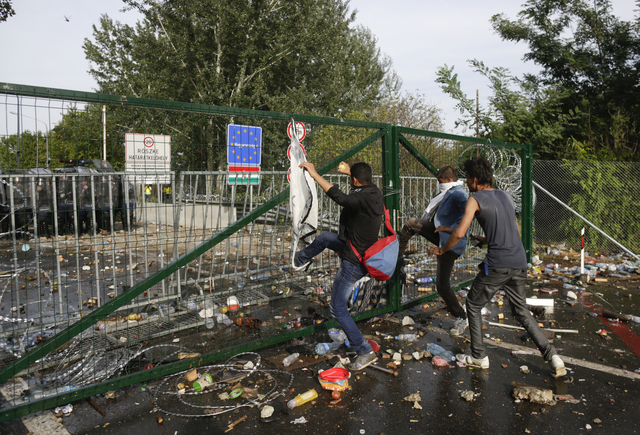 Migrants kick the fence on the Serbian side of the border as Hungarian riot police fires tear gas and water cannon near Roszke