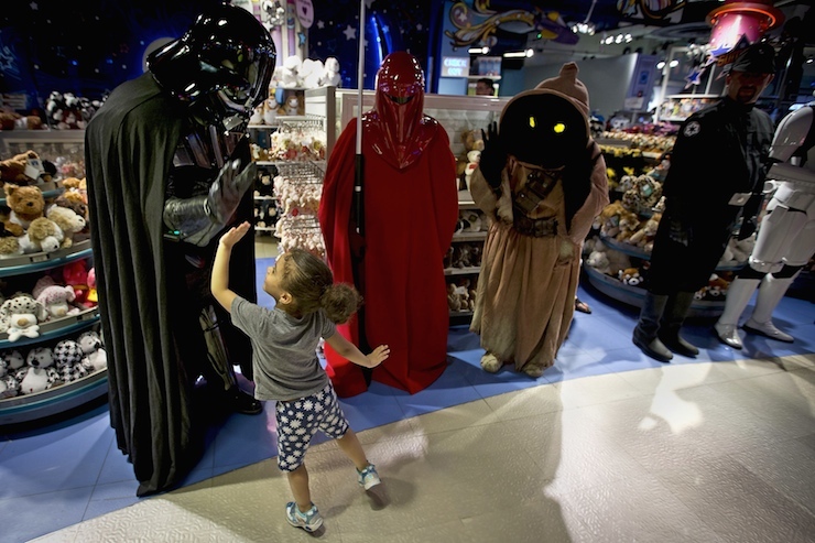 A man dressed as Darth Vader from "Star Wars" high fives a child as people arrive to purchase toys that went on sale at midnight in advance of the film "Star Wars: The Force Awakens" in Times Square in New York