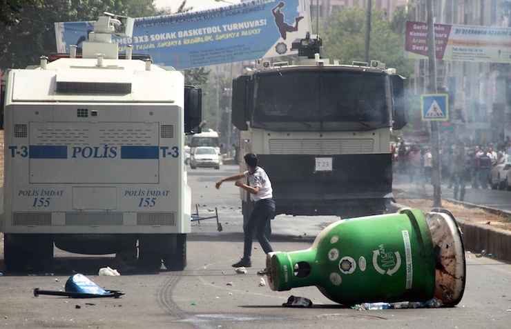 Protester throws stones at police vehicles in the Kurdish dominated southeastern city of Diyarbakir, Turkey