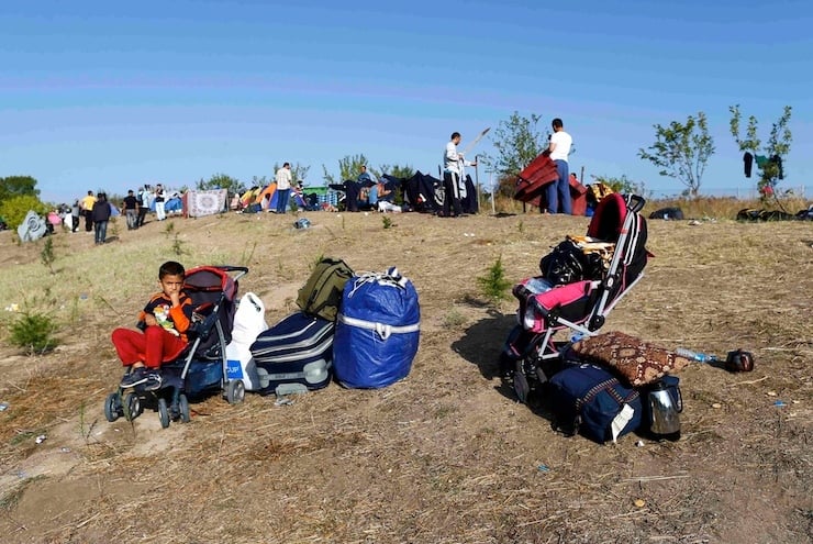 A boy sits in a stroller as migrants camp during their walk towards the Greek border near Edirne