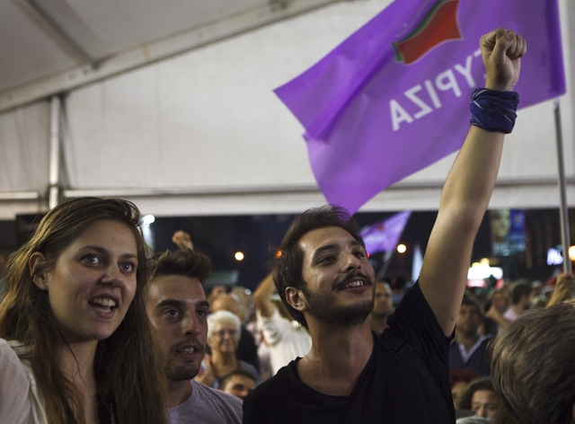 Supporters of leftist Syriza party react at the party's main election kiosk after seeing early results following a general election in Athens