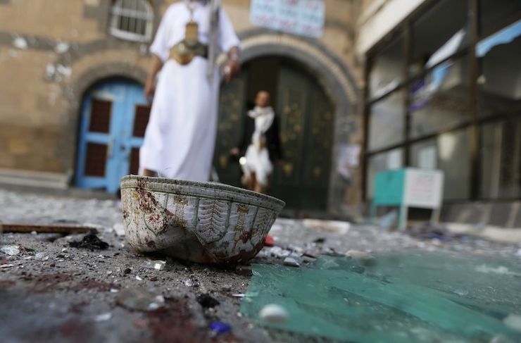 People walk past a headgear lying on the ground at the al-Balili mosque after two bombings at the mosque in Yemen's capital Sanaa