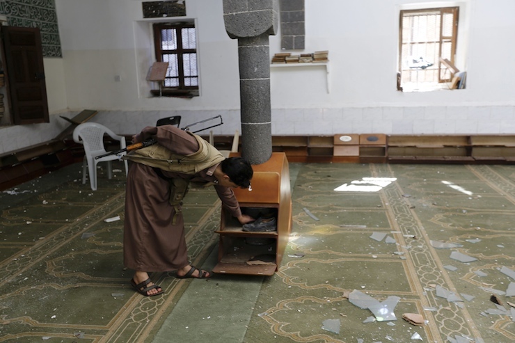 Houthi militant checks shoes inside the al-Balili mosque after two bombings hit the mosque in Yemen's capital Sanaa