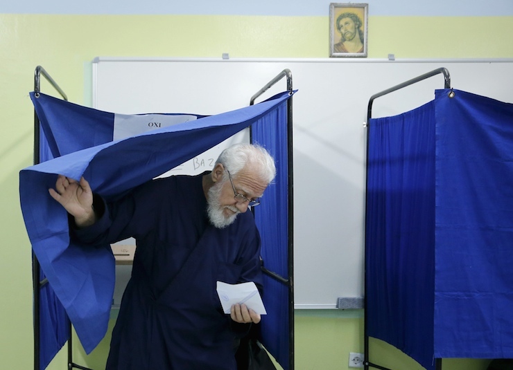 A Greek orthodox priest exits a voting booth holding his ballot before voting in a general election at a polling station in Athens