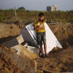 A Palestinian boy rests at a fridge at the scene of a house that was brought down by an Israeli air strike that killed a woman and her 3-year-old daughter in Gaza