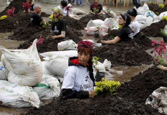 Protesters sit with mock graves of the disappeared during a protest against Colombian army's Operation Orion, a 2002 military operation in the Comuna 13 neighborhood, in Medellin
