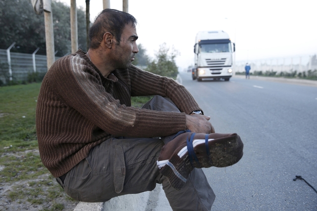 Iranian refugee Youssef, 33-years-old, sits along a road close to the "new jungle" in Calais, France, October 3, 2015. Youssef, with his feet wrapped in pieces cut from clothing, reportedly walked 10 kilometers through the Channel Tunnel overnight, before being stopped by police and security. Around 200 migrants tried to get into the Channel Tunnel in France overnight, clashing with staff and police and forcing the suspension of rails services a spokesman for Eurotunnel said. Around 3,000 migrants fleeing war and poverty in Africa and the Middle East are camped on the French side of the tunnel in Calais, trying to board vehicles heading for Britain via the tunnel and on ferries or by walking through the tunnel, even though security measures aimed at keeping them out have been stepped up. REUTERS/Pascal Rossignol