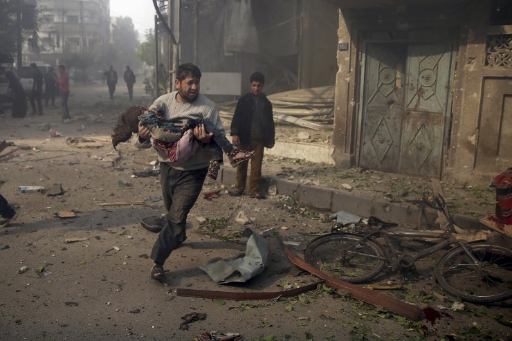 A man carries an injured girl as he rushes away from a site hit by what activists said were airstrikes by forces loyal to Syria's President Bashar al-Assad, in the Douma neighborhood of Damascus, Syria