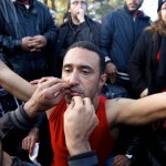 A stranded Iranian migrant has his mouth sewed shut by a colleague during a protest at the Greek-Macedonian border near the Greek village of Idomeni