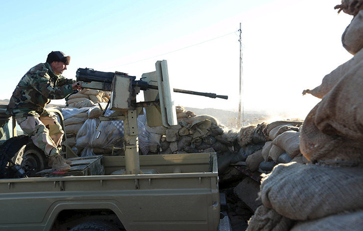A member of the Kurdish Peshmerga forces fires his weapon during clashes with Islamic State militants in the town of Sinjar