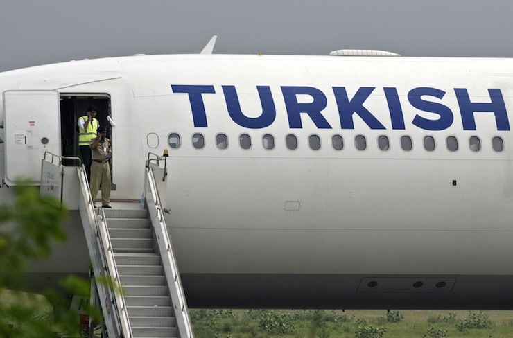 Security personnel make calls on mobile phones at a door of a Turkish Airlines passenger jet after it made an emergency landing at the Indira Gandhi International Airport in New Delhi July 7, 2015. The Turkish Airlines flight from Bangkok made an emergency landing in New Delhi after a written bomb threat was found in a toilet on the Airbus A330 jet carrying 134 passengers, the airline and Indian security sources said. REUTERS/Stringer