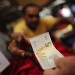 A vendor gets a five Euro bank note from a customer at the central market in Athens