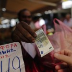 A vendor gives a five Euro bank note back to a customer at the central market in Athens