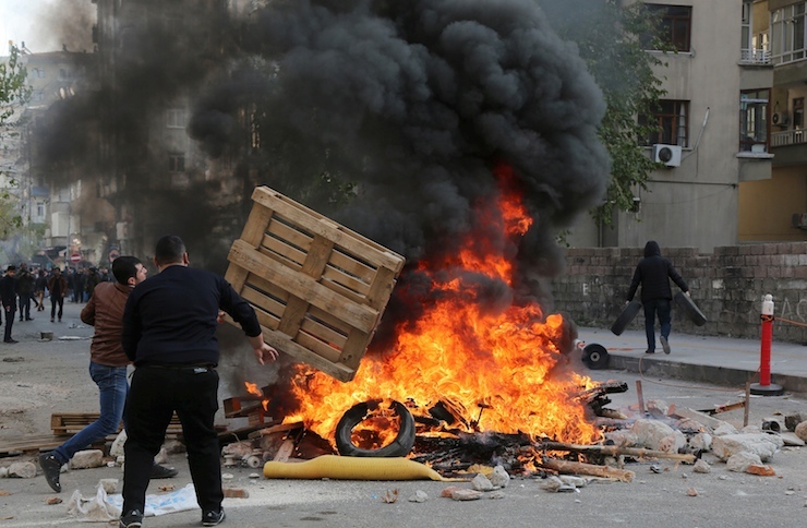 Demonstrators set tyres on fire as they clash with riot police during a protest against the curfew in Sur district, in the southeastern city of Diyarbakir, Turkey