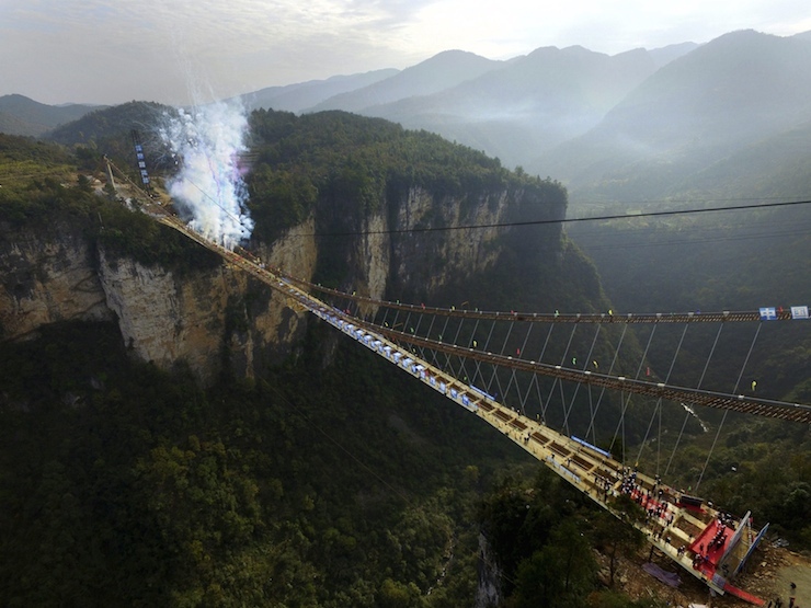 Fireworks go off to celebrate completion of construction of steel box girder on glass bridge as it suspends over canyon in Zhangjiajie National Park