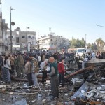Syrian army soldiers and civilians inspect the site of two bomb explosions in the Syrian city of Homs