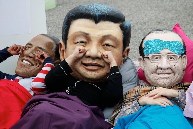 Activists of global anti-poverty charity Oxfam wearing masks depicting some of the world leaders stage a protest outside the venue of the World Climate Change Conference 2015 in Le Bourget, near Paris