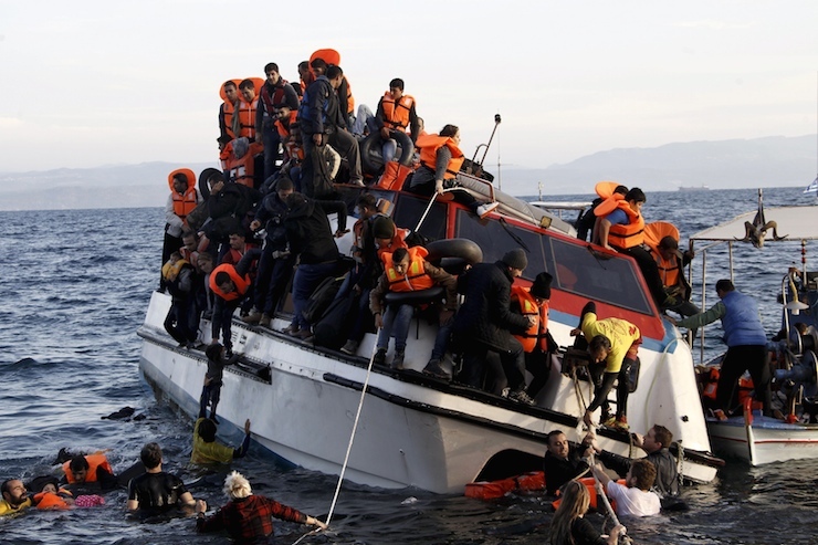 Refugees, most of them Syrians, struggle to leave a half-sunken catamaran carrying around 150 refugees as it arrives on the Greek island of Lesbos