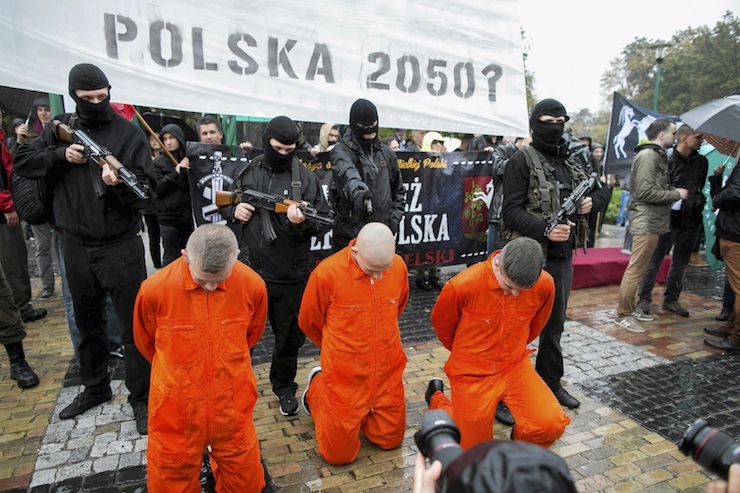Participants re-enact a scene of prisoners being shot in the style of Islamic State videos during an anti-migrant demonstration of far-right organizations in Lublin