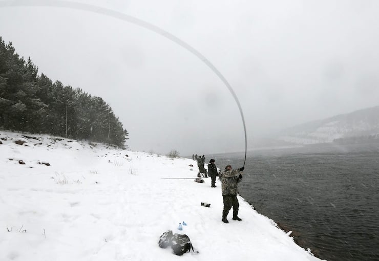 Men fish during snowfall on a bank of the Yenisei River outside Siberian city of Krasnoyarsk, Russia