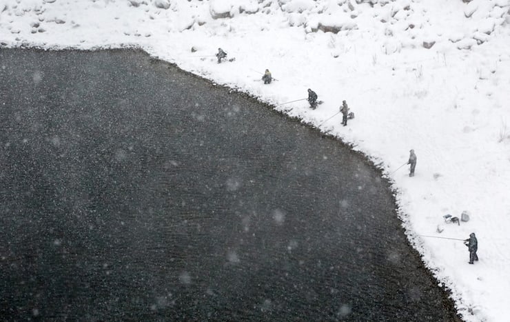 Men fish during snowfall on a bank of the Yenisei River outside Siberian city of Krasnoyarsk, Russia