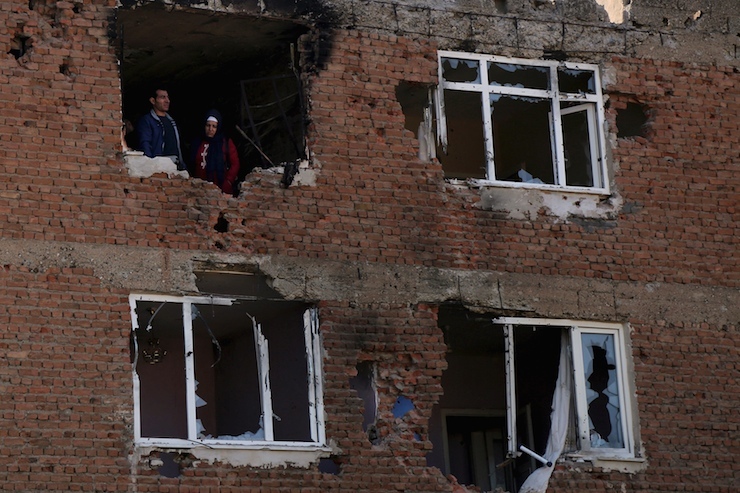 People look out from a building which was damaged during the security operations and clashes between Turkish security forces and Kurdish militants, in Sur district of Diyarbakir, Turkey
