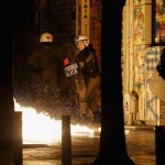 A petrol bomb explodes next to a riot police officer during clashes with hooded youth in Athens