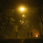 Hooded youth walk amidst tear gas smoke during clashes with clashes with riot police in Athens