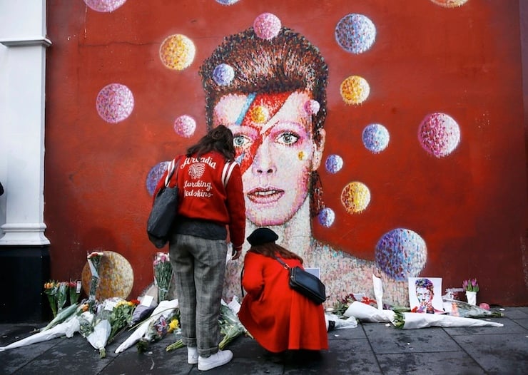 Two women stop at a mural of David Bowie in Brixton, south London, January 11, 2016. David Bowie, a music legend who used daringly androgynous displays of sexuality and glittering costumes to frame legendary rock hits "Ziggy Stardust" and "Space Oddity", has died of cancer. REUTERS/Stefan Wermuth