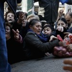People reach out to receive free produce handed out by farmers in protest over the government's proposal to overhaul the country's ailing pension system in Athens