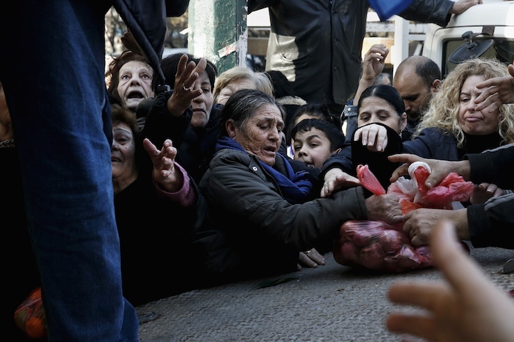 People reach out to receive free produce handed out by farmers in protest over the government's proposal to overhaul the country's ailing pension system in Athens