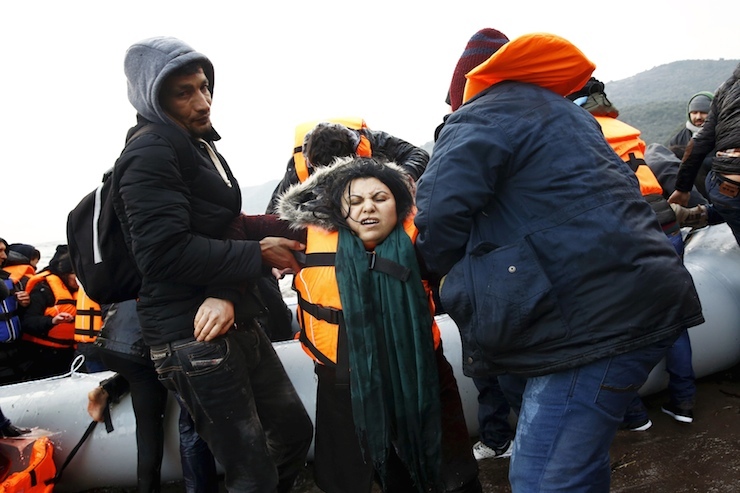 An Iraqi refugee is aided out of a dinghy, moments after arriving on a beach on the Greek island of Lesbos