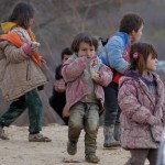 Internally displaced children, covered with mud, wait with their families as they are stuck in the town of Khirbet Al-Joz, in Latakia countryside, waiting to get permission to cross into Turkey near the Syrian-Turkish border